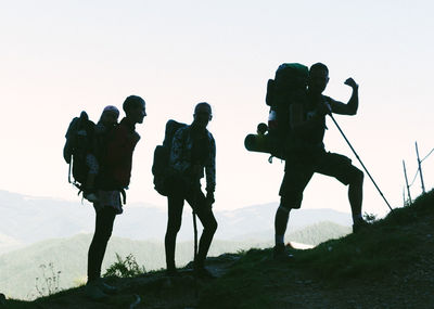 Hikers standing on mountain against clear sky