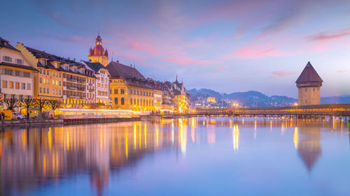 Reflection of illuminated buildings in city at sunset