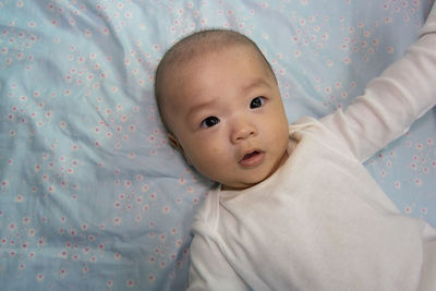 Portrait of cute baby lying on bed