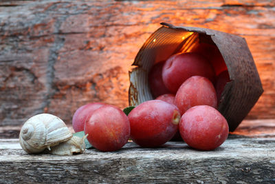 Plums on rustic table next to snail