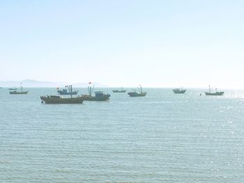 Boats in sea against clear sky