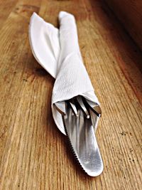 Close-up of cutlery wrapped into paper napkin on table