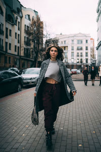 Portrait of young woman standing on street in city