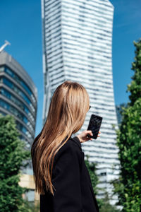 Young woman with mobile phone on modern downtown high-rises skyscrapers street city view background