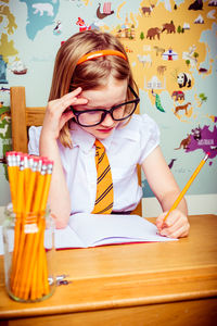 Tensed girl writing in book on desk