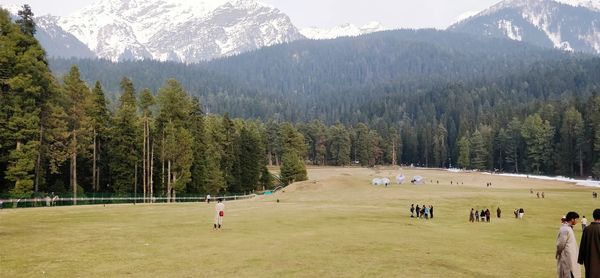 People on field against mountains