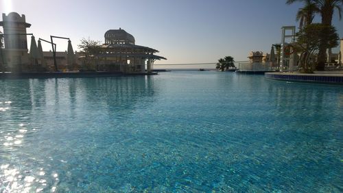 Swimming pool by sea against clear sky