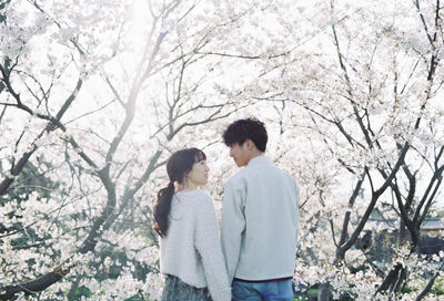 Rear view of couple kissing against trees