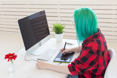 Midsection of woman using mobile phone while sitting on table