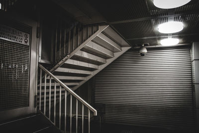 Gate on staircase against shutter in illuminated building