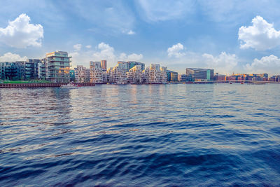 Buildings by sea against sky