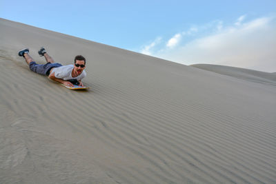 Full length of man sandboarding in desert