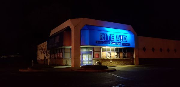 Illuminated sign on road by building in city at night