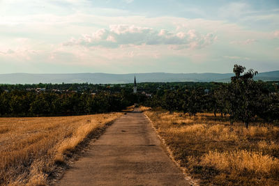 Road amidst field against sky