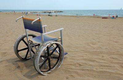 Deck chairs on beach against sky