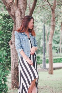 Full length of woman standing on tree trunk