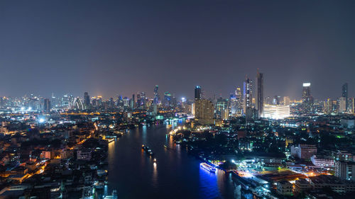 Illuminated buildings in city against sky at night