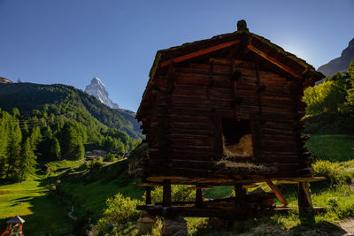 House on field by mountain against sky