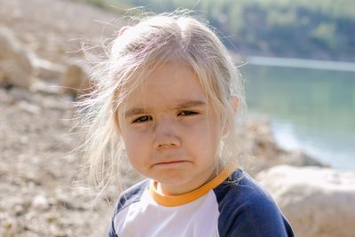 Little girl with blond hair looking at the camera with a sad expression on her face