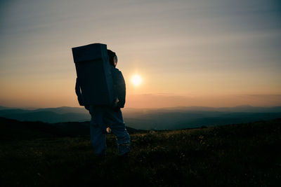 Man standing on field against sky during sunset