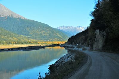 Scenic view of lake and mountains against clear blue sky