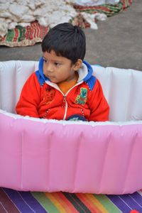 Cute boy looking away while sitting on sofa