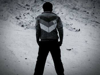 Rear view of a man standing on sand