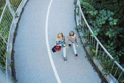 High angle view of girls walking on bridge amidst trees