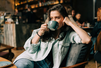 Young beautiful woman sitting in a coffee shop drinks coffee.