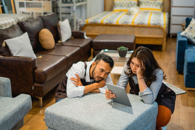 Side view of woman using mobile phone while sitting on sofa at home