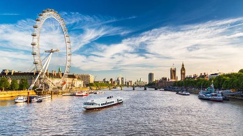 Ferris wheel by river in city