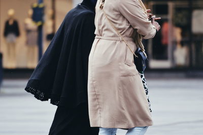 Midsection of woman with umbrella walking on street