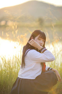 Side view of young woman sitting on field