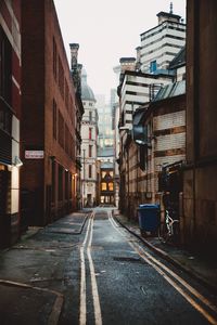 Road amidst buildings in city against sky