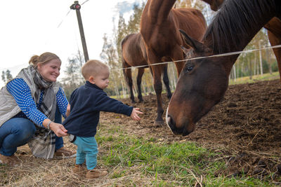 Mother and son playing with horses in ranch