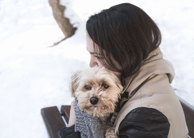 Close-up of woman holding dog on snow covered field