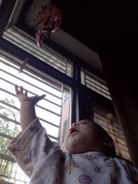 Low angle view of baby girl on window at home