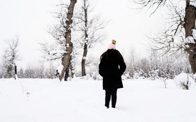 Rear view of woman standing on snow covered landscape