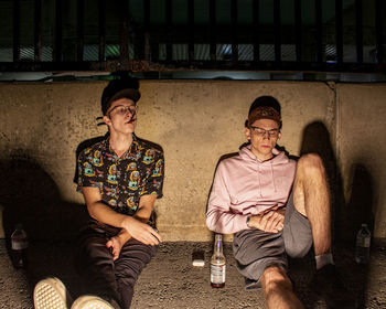 Full length of young man drinking glass sitting outdoors