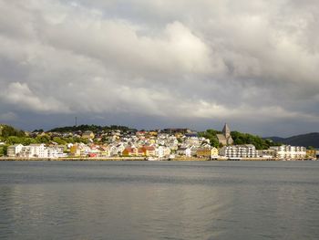 Buildings by river against sky in city