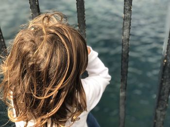 High angle view of girl looking at sea through railing