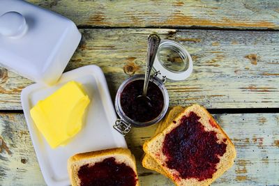 Jam, butter in butter dish and jam spread on toast. healthy and diet concept. rural white wooden