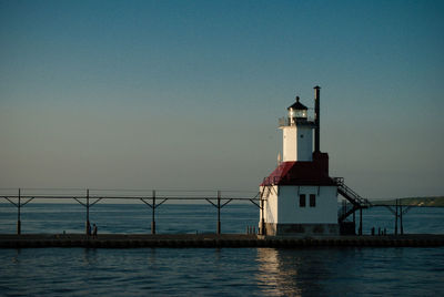 Lighthouse by sea against sky