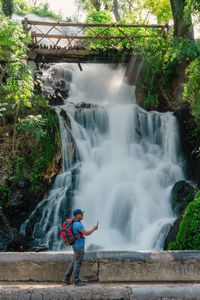 Rear view of man standing against waterfall