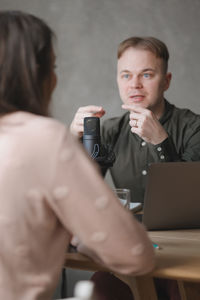 Young woman using phone while sitting on table