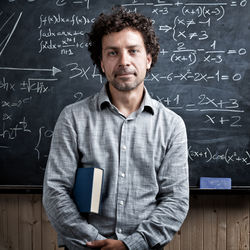 Portrait of teacher standing by blackboard