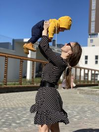 Woman with arms raised standing in city