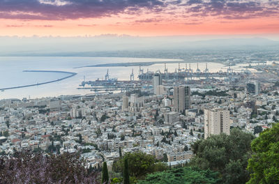 High angle view of buildings and sea against sky during sunset