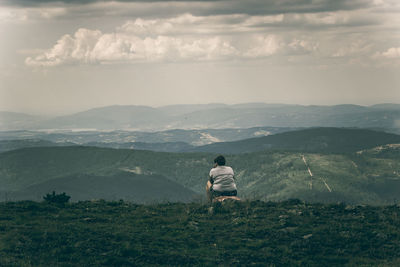 Rear view of man on mountain against sky