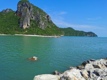 Scenic view of sea and rocks against blue sky